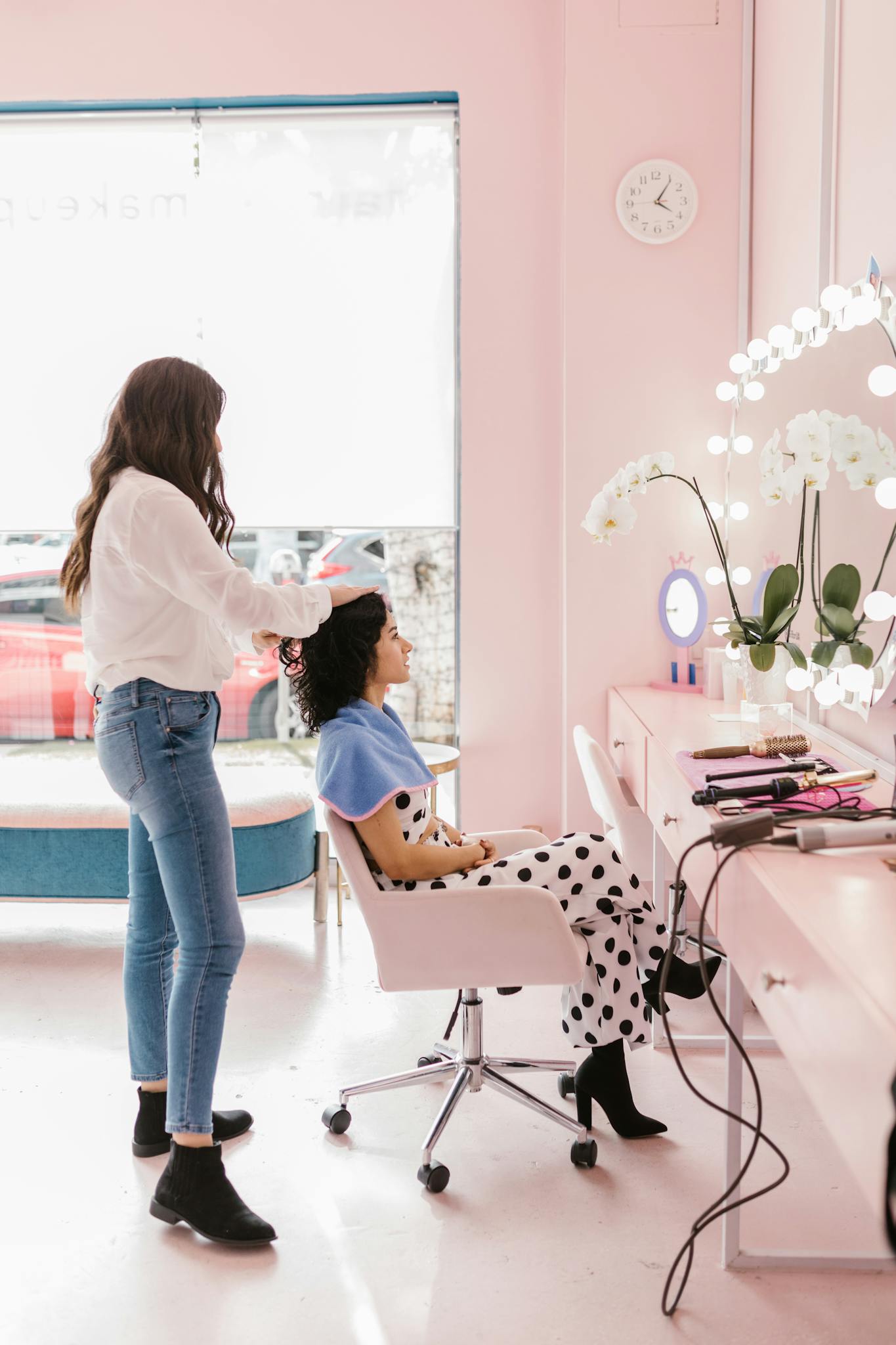 Hairdresser styling client's hair in a modern salon setting with soft lighting.